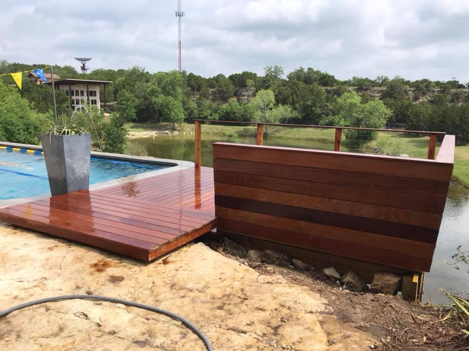 There is a wooden deck next to a swimming pool.