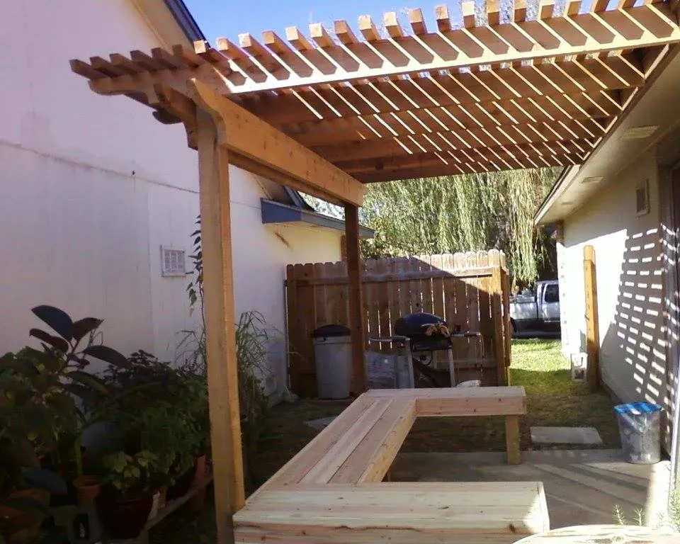 A wooden pergola with a bench underneath it