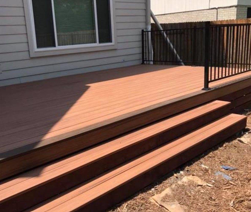 A wooden deck with stairs leading up to it next to a house.