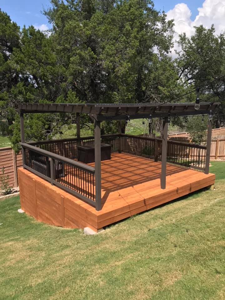 A wooden deck with a pergola on top of it in a backyard.