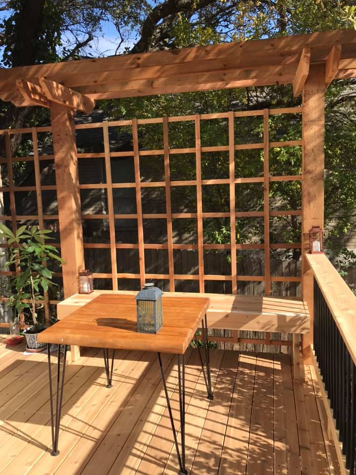 A wooden deck with a table and chairs under a wooden pergola.