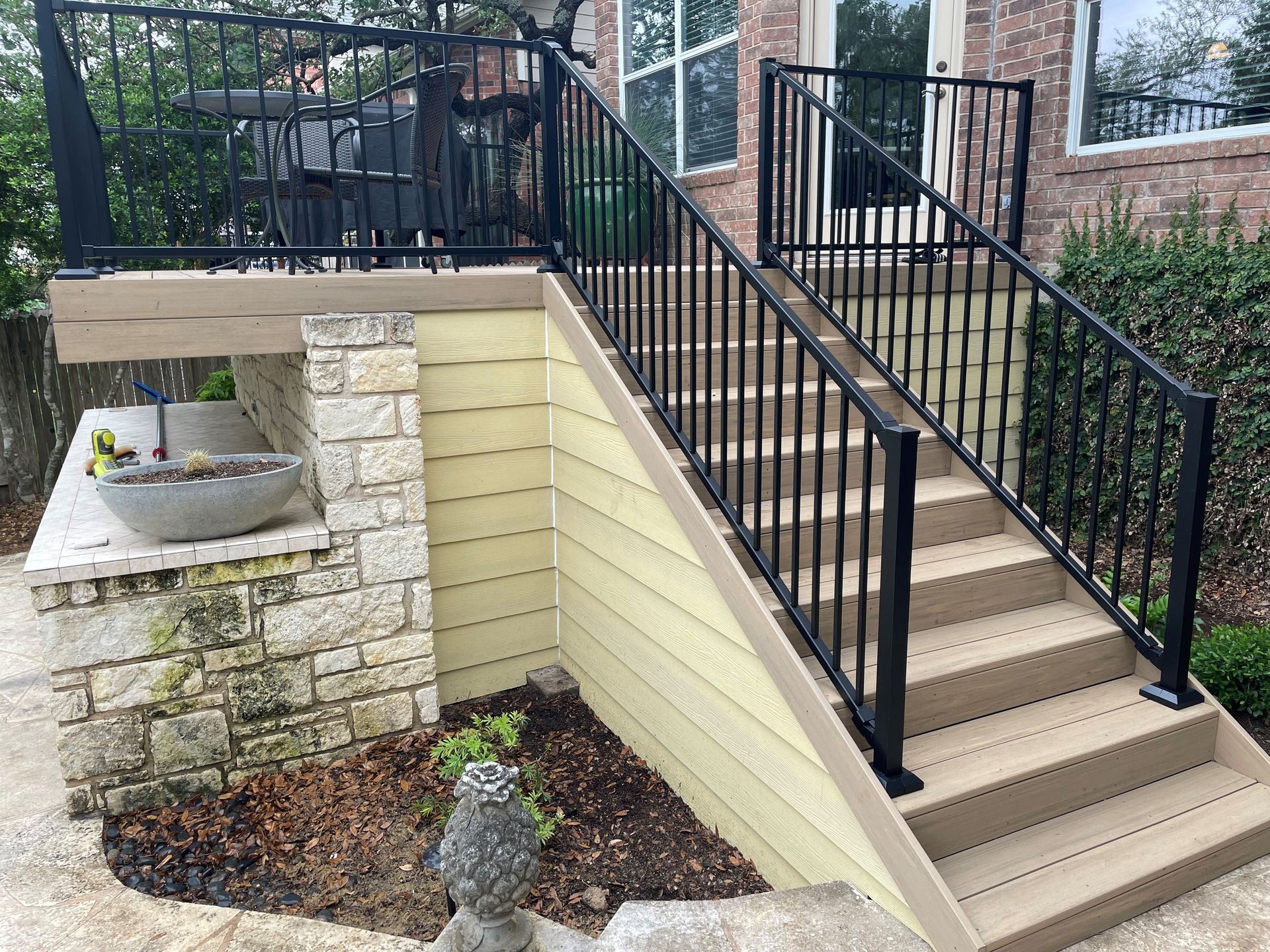 A deck with stairs leading up to it and a black railing.