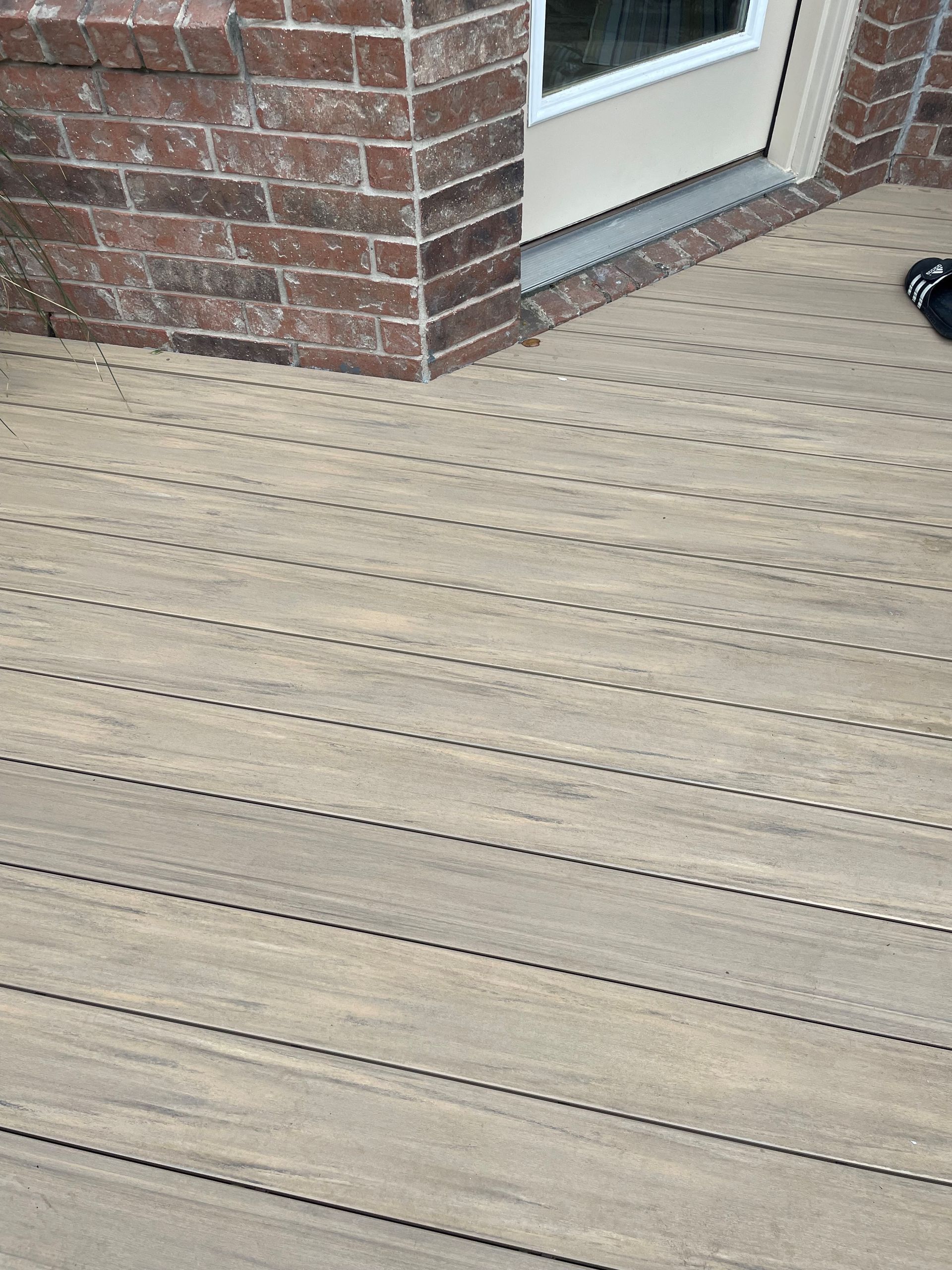 A wooden deck with a brick wall in the background.