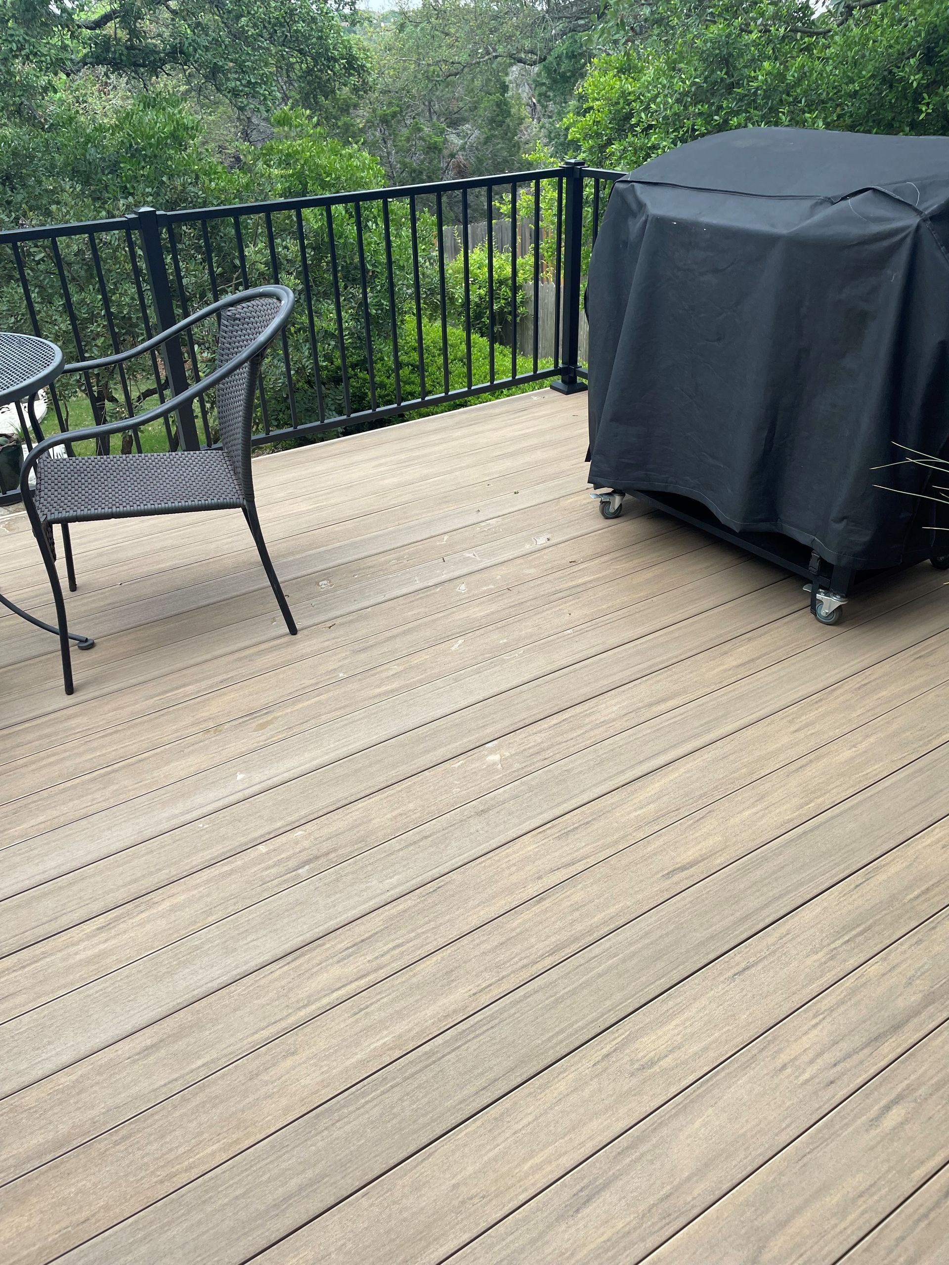 A wooden deck with a table and chairs and a grill.