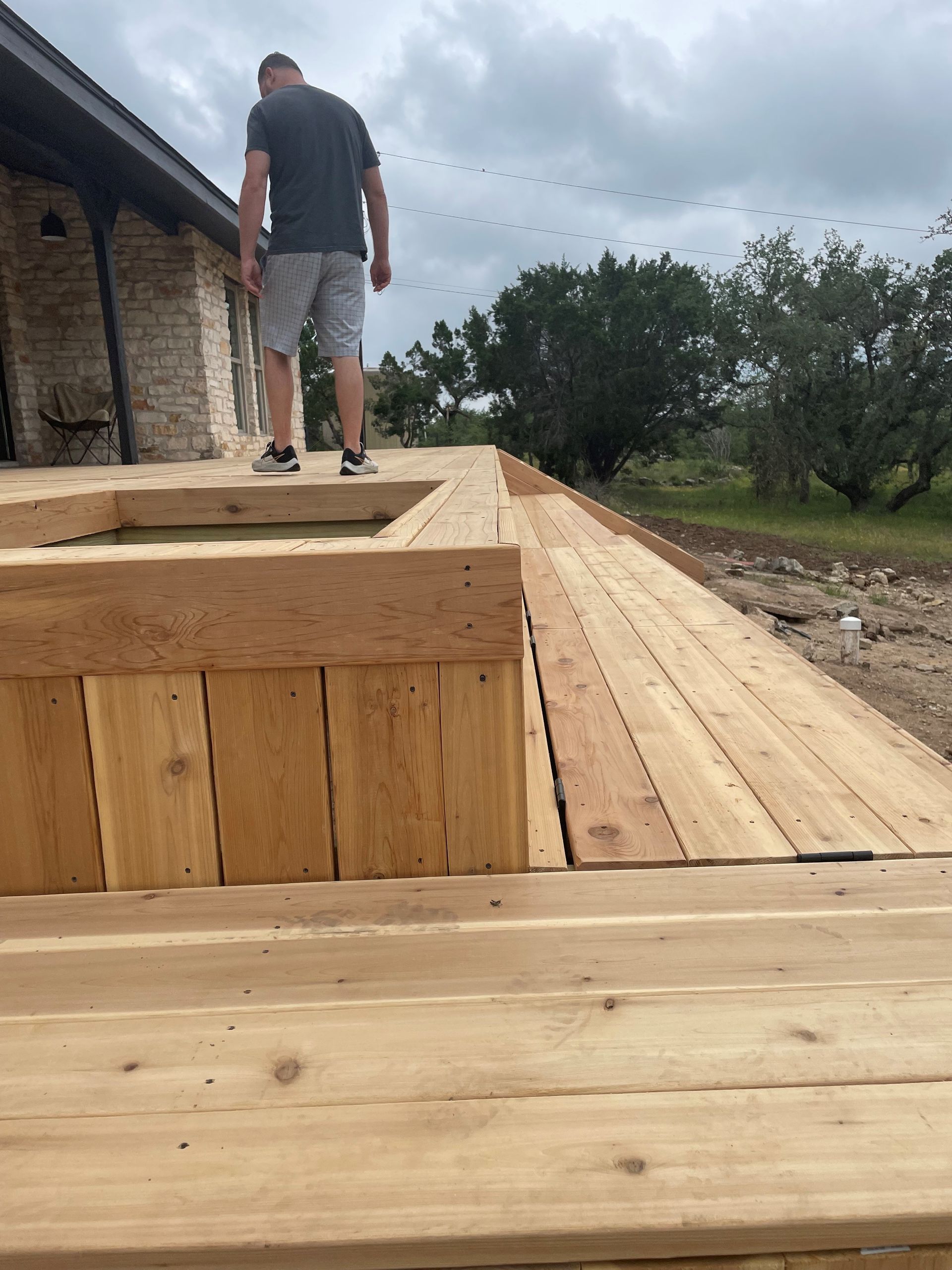 A man is standing on top of a wooden deck.