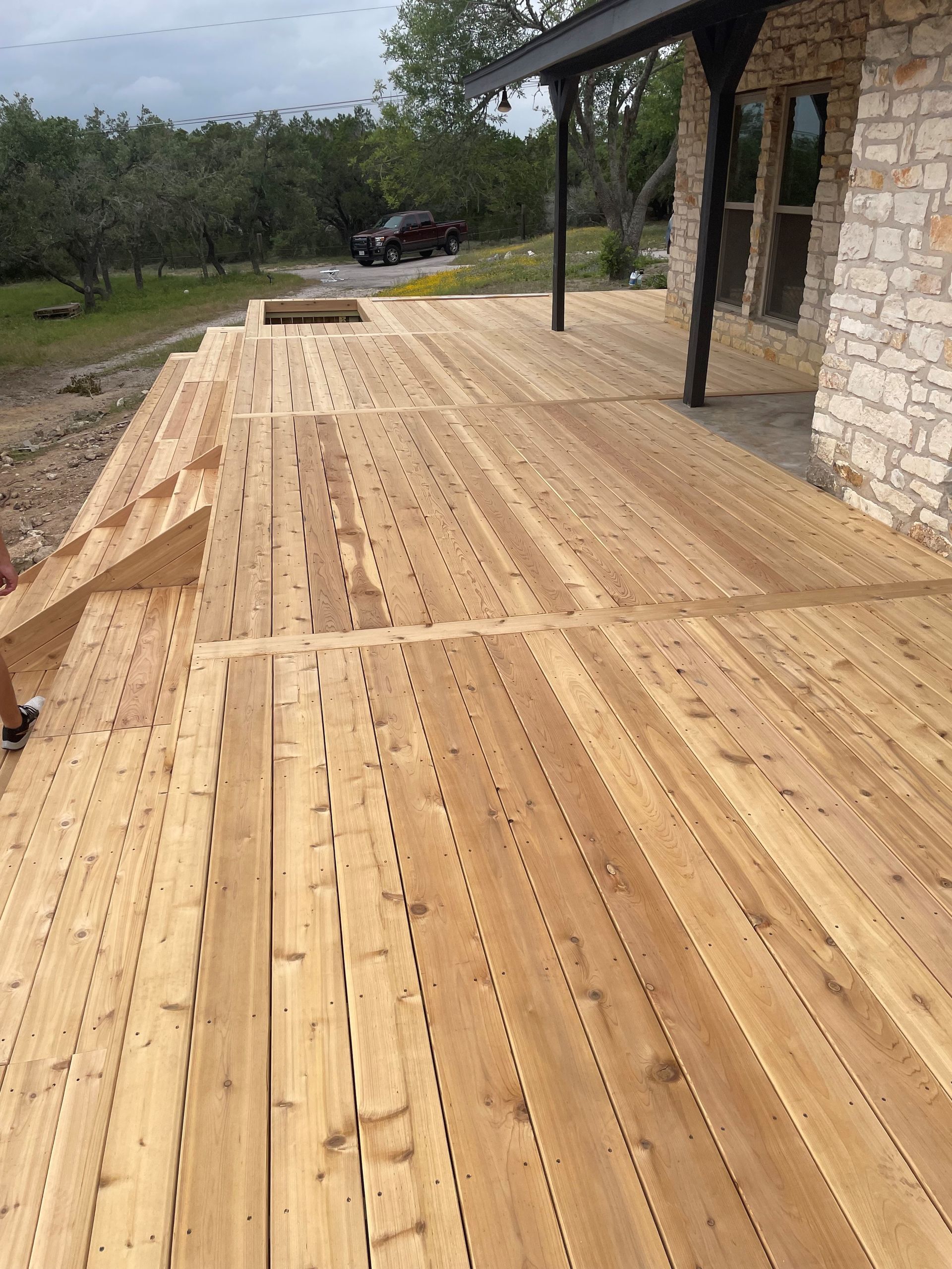 A wooden deck is being built in front of a stone house.