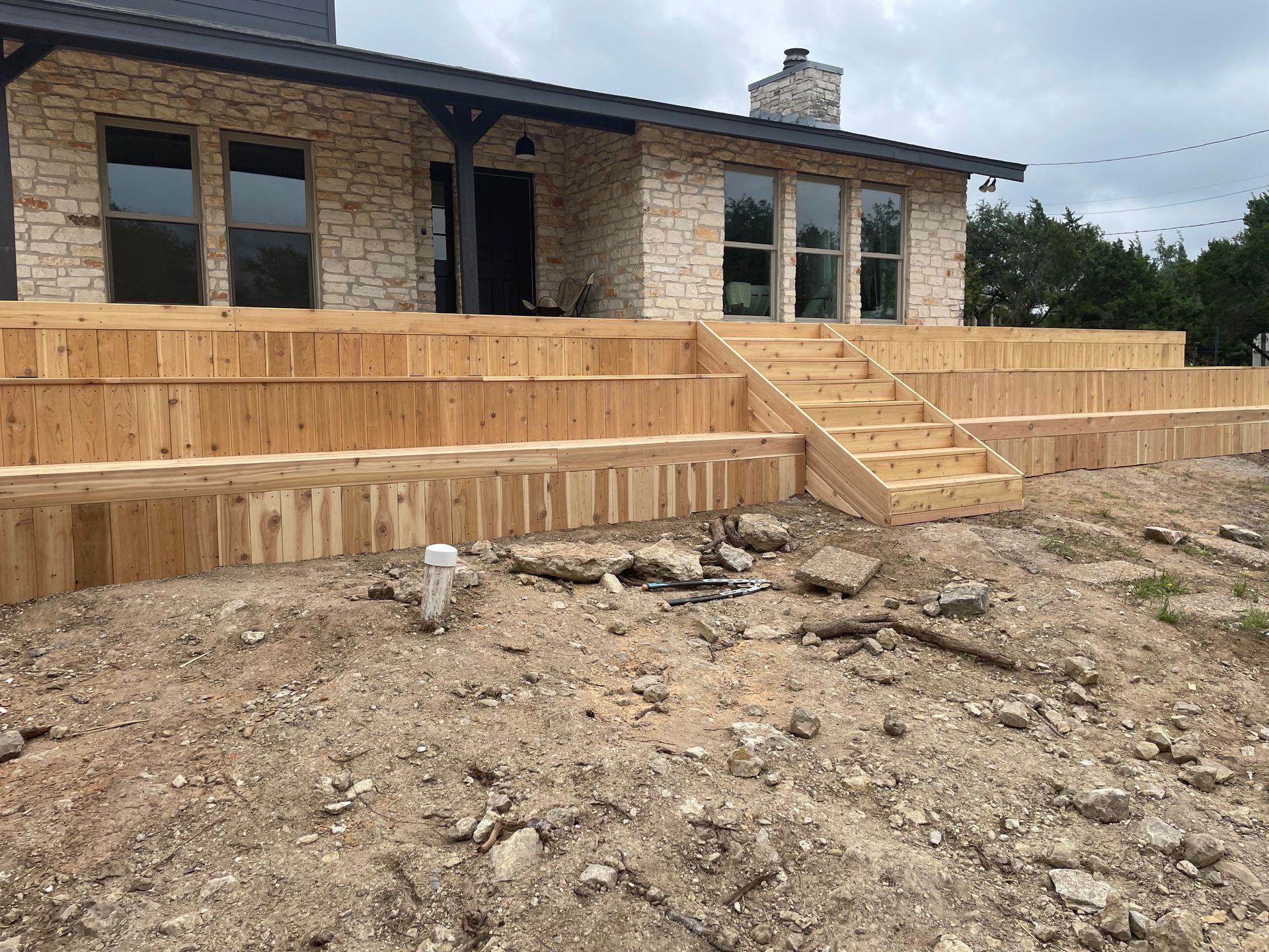 A wooden deck is being built in front of a stone house.
