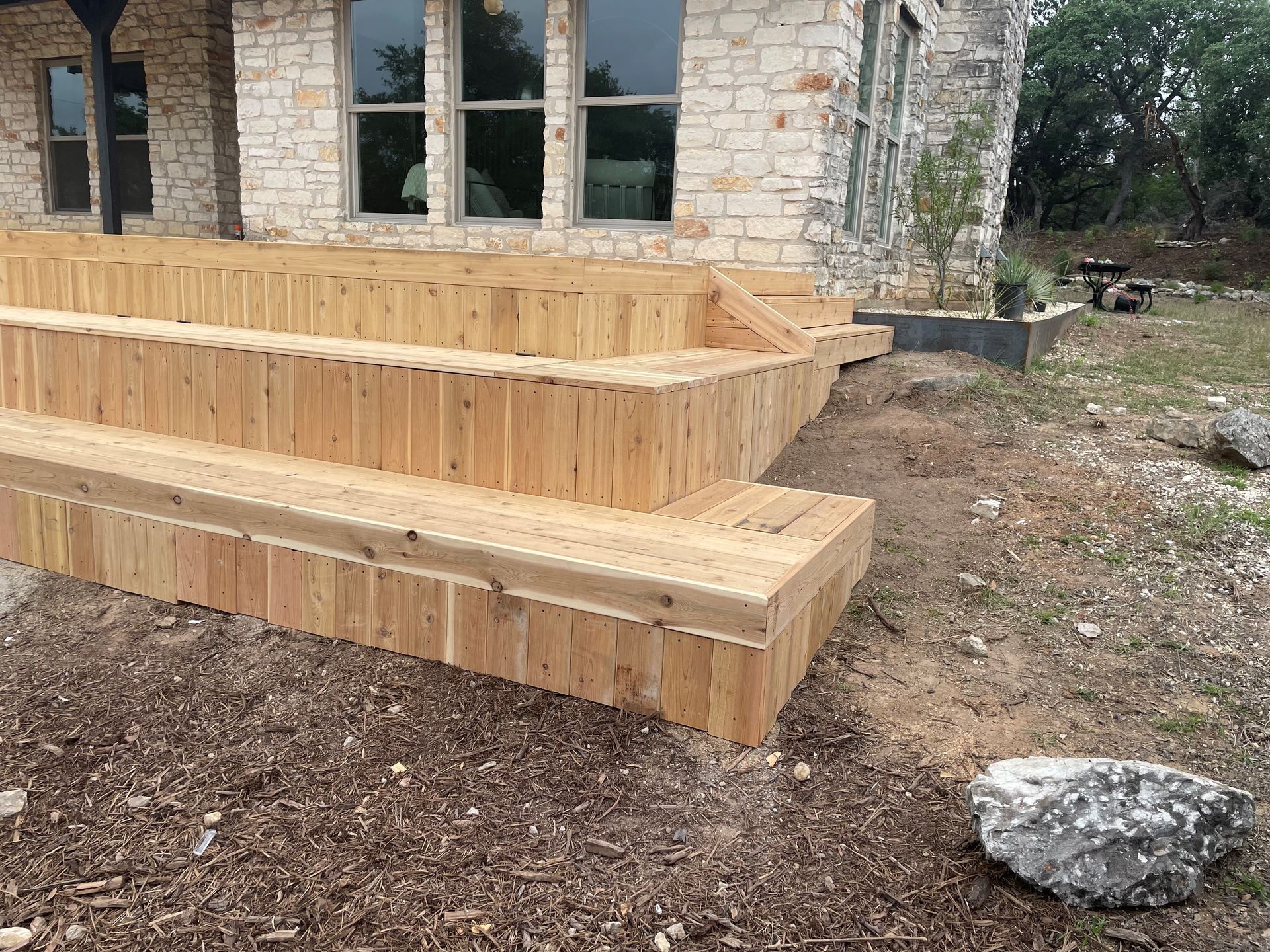 A wooden deck is being built in front of a stone house.