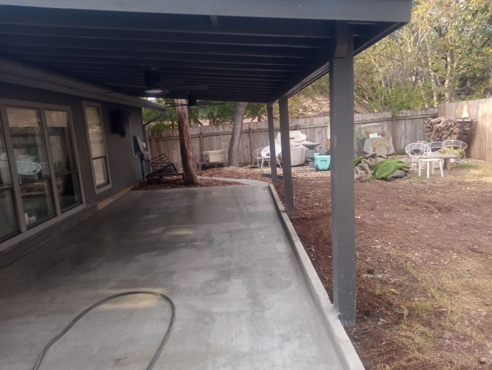 A covered patio in the backyard of a house