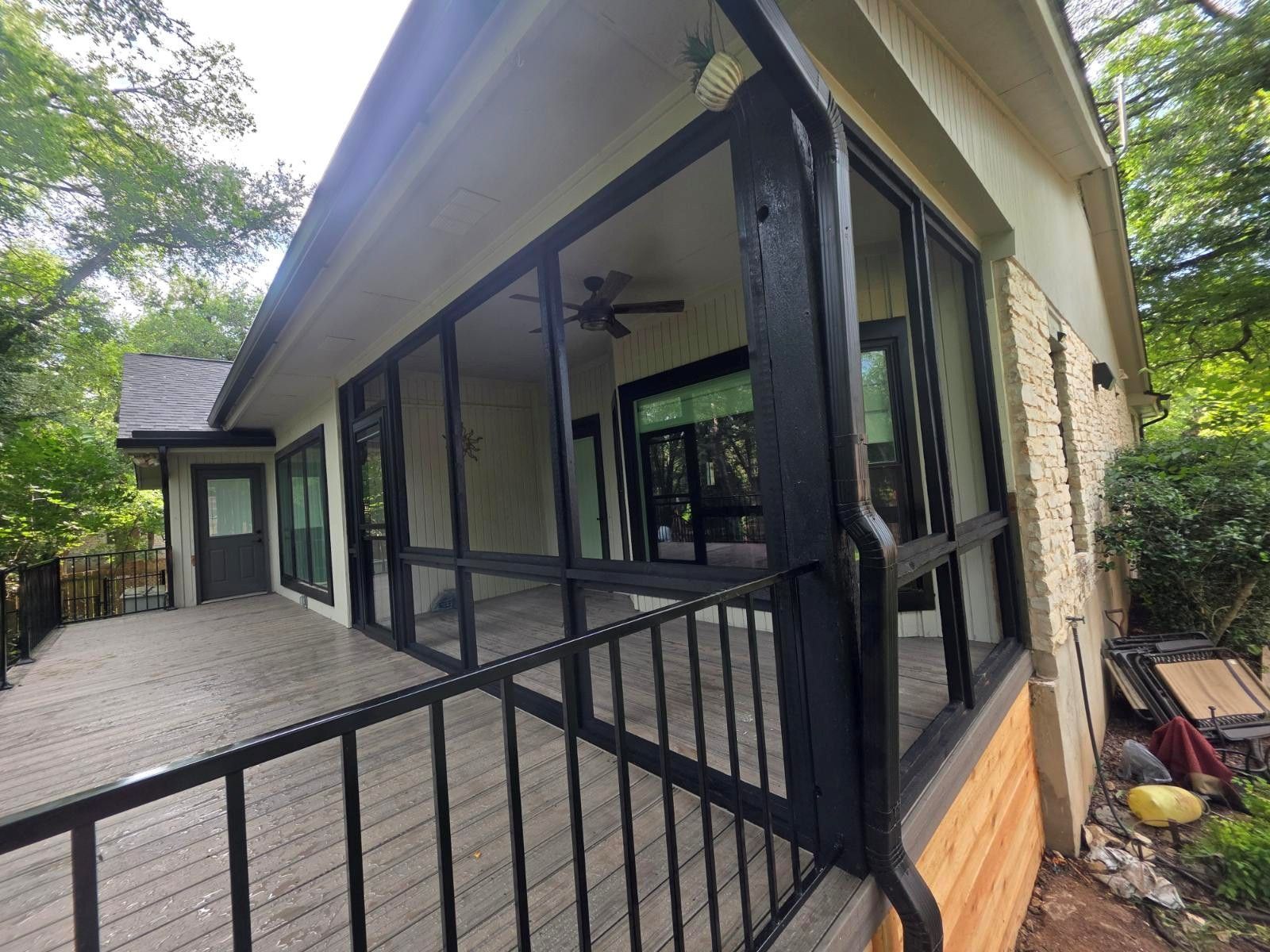 A screened in porch with a lot of windows and a ceiling fan.