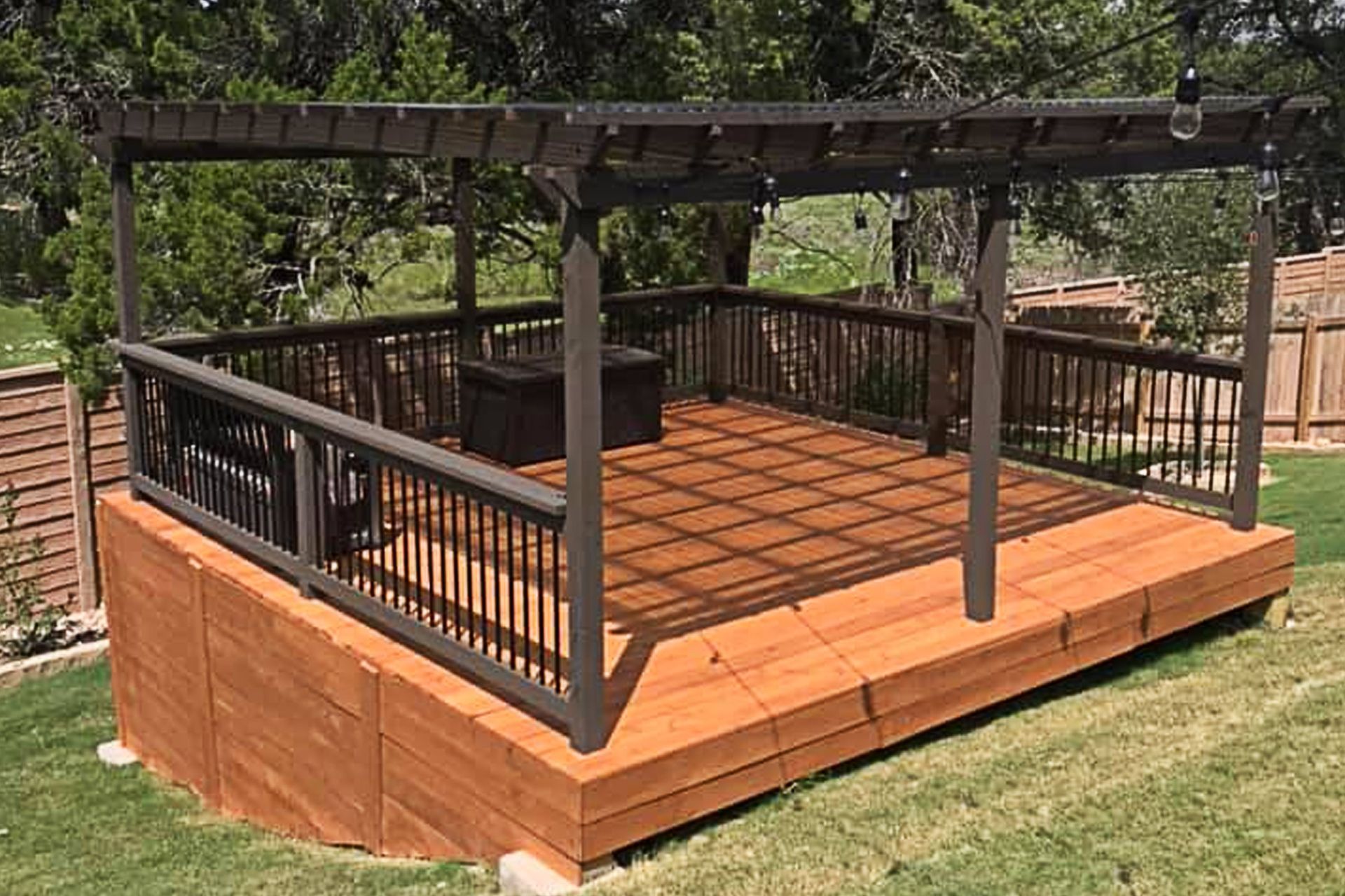 A wooden deck with a pergola over it in a backyard.