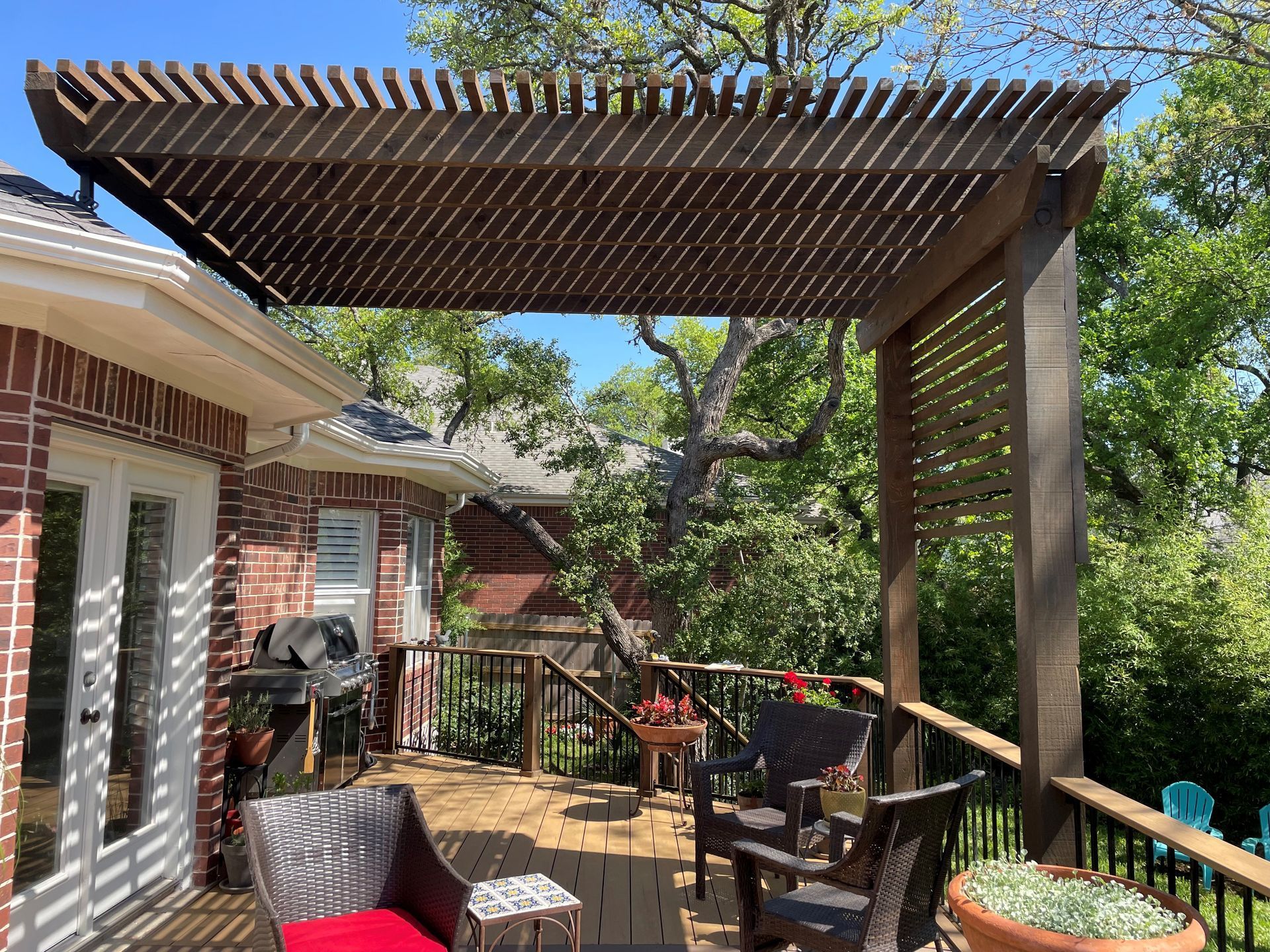 There is a pergola on the deck of a house.