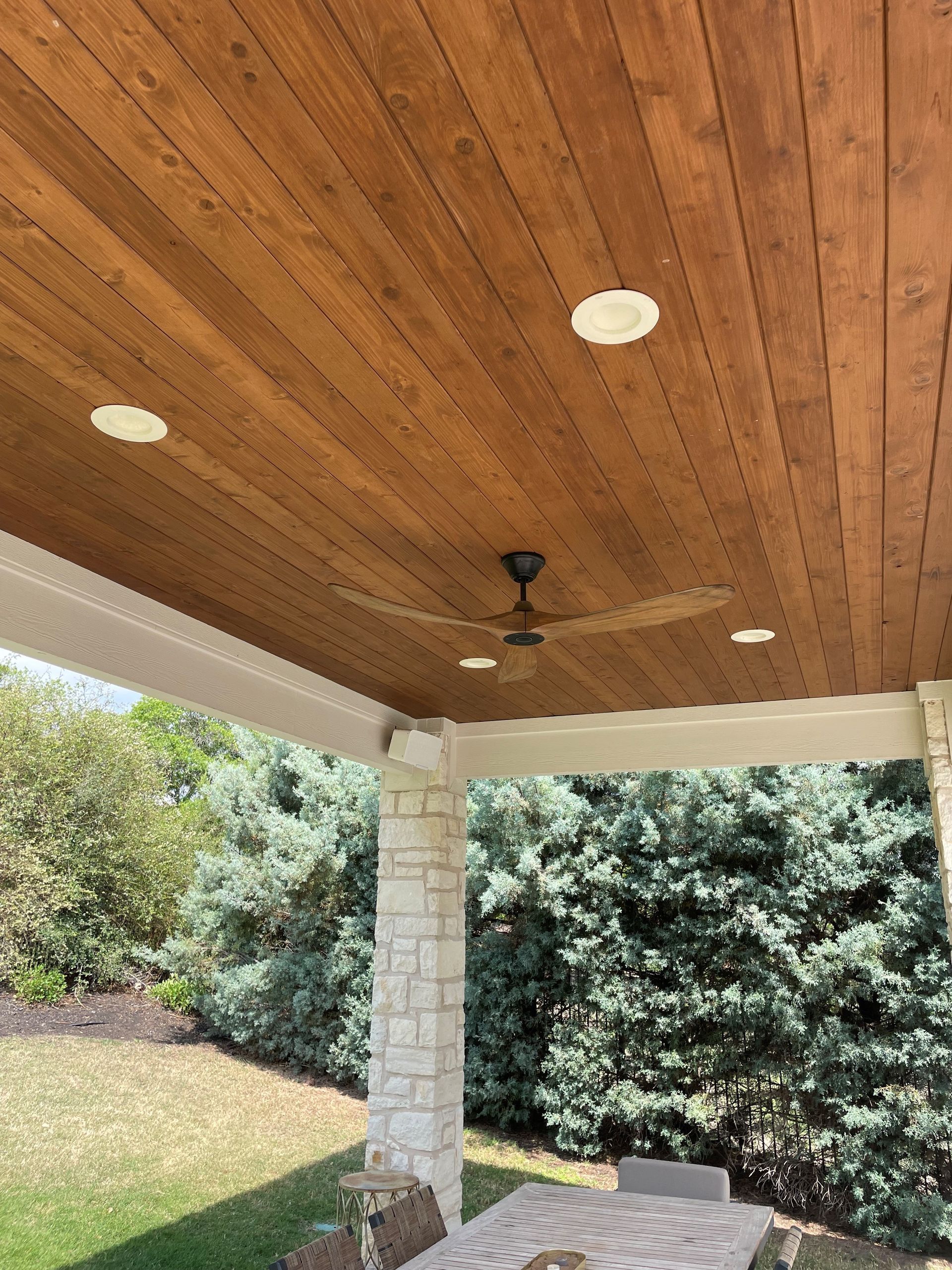 A ceiling fan is hanging from the ceiling of a wooden porch.