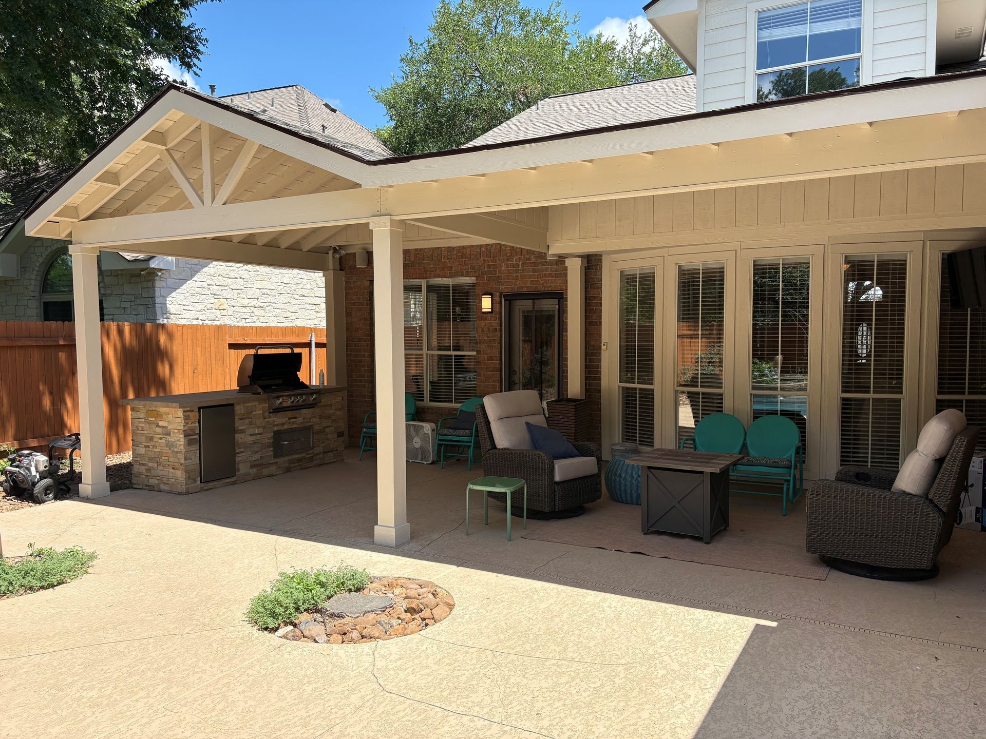 Covered patio with brick fireplace, outdoor chairs, and a gravel courtyard