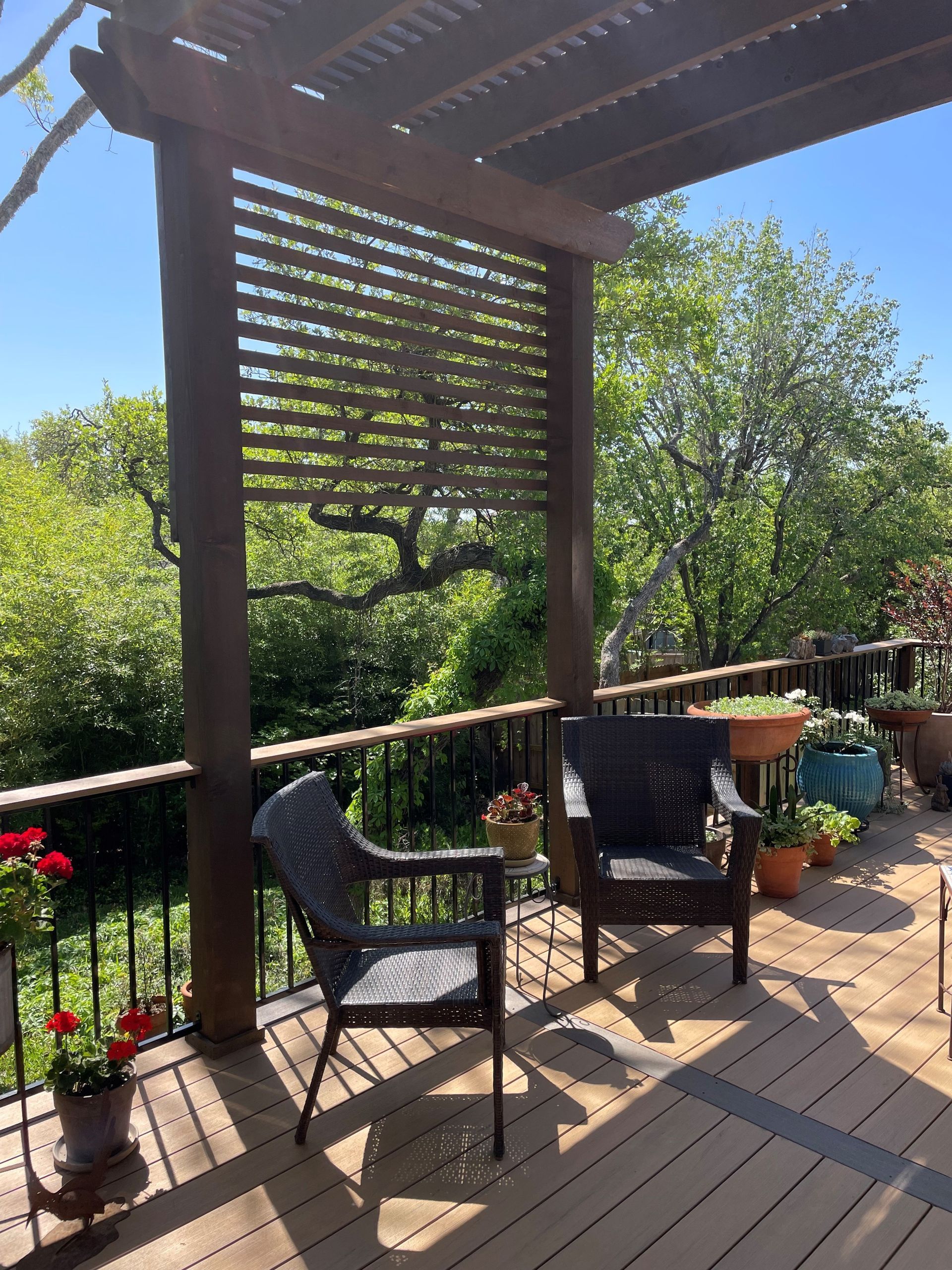 A deck with two chairs and a table under a pergola