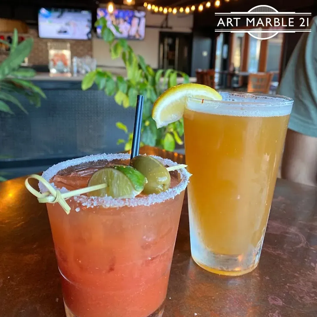 Bloody Mary with olives and beer with lemon, on a bar.