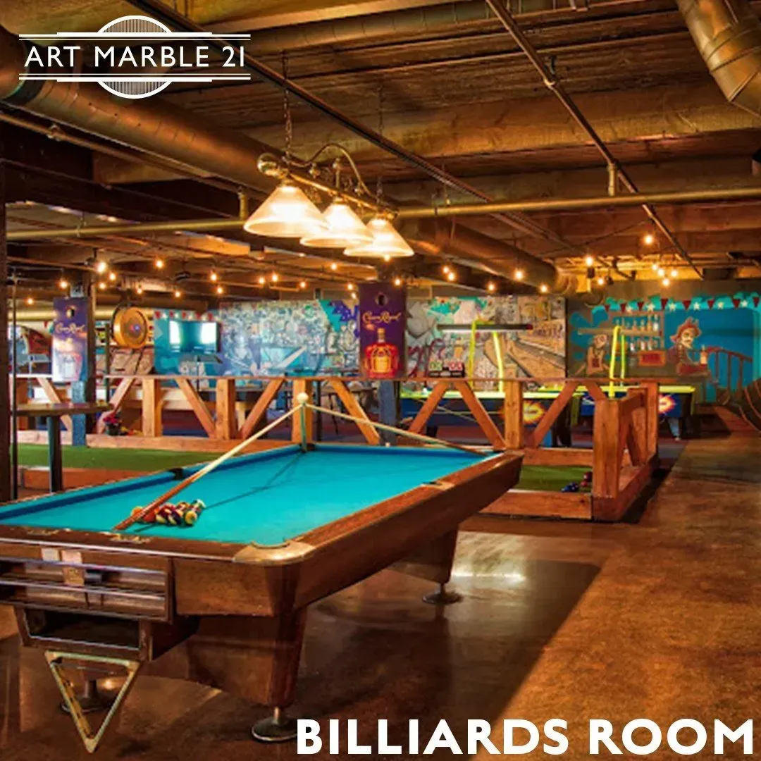 Billiards room interior with pool table and exposed ceiling, featuring colorful murals, and overhead lighting.