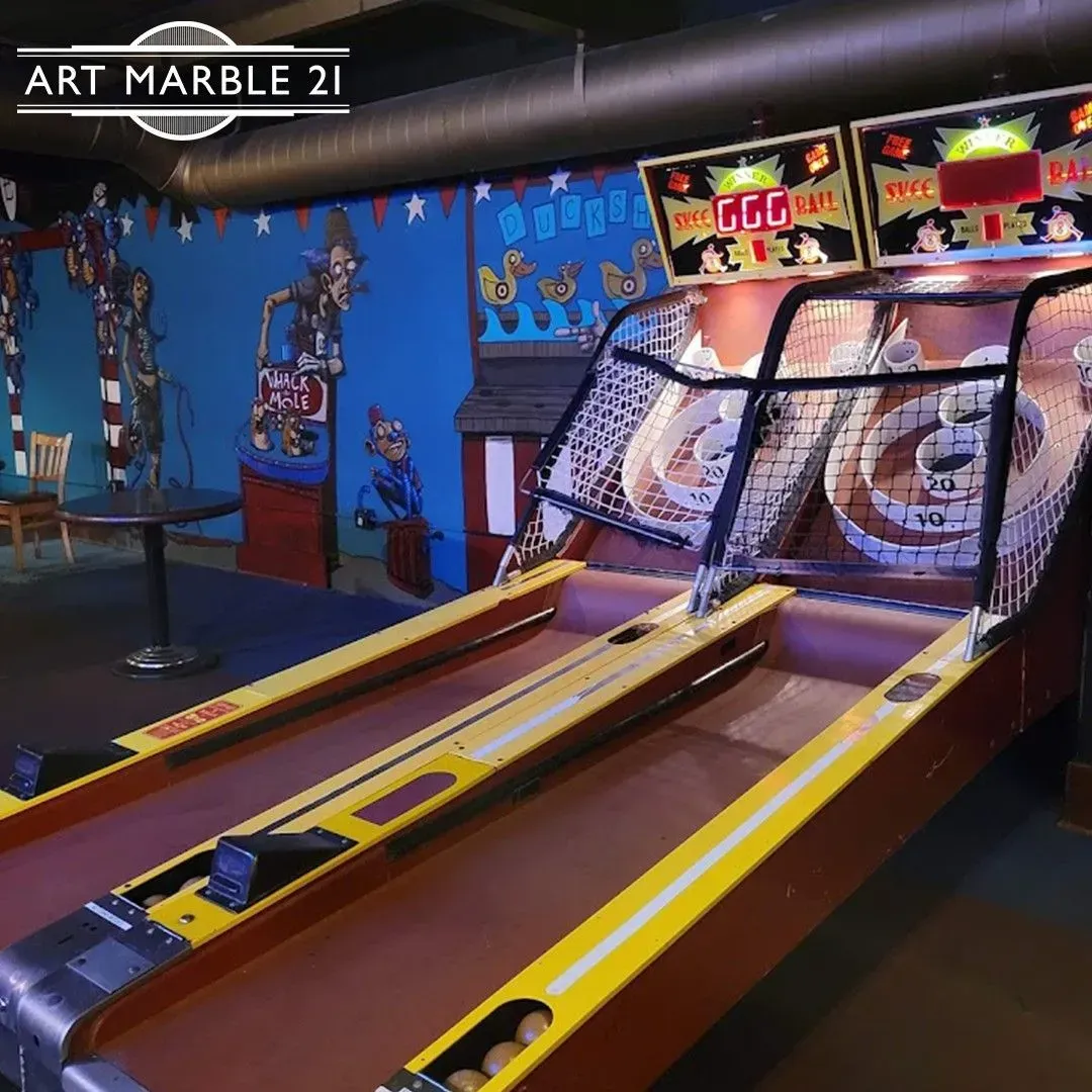 Skee-ball arcade game. Two lanes, yellow and brown. Scores displayed above. Colorful mural background.