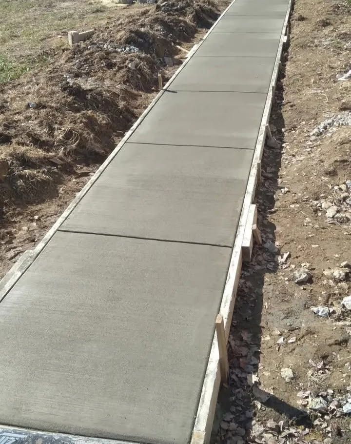 Concrete sidewalk under construction along a dirt embankment