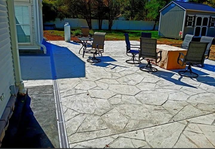 Patio with stone paving, outdoor chairs, and a small table beside a house in bright sunlight
