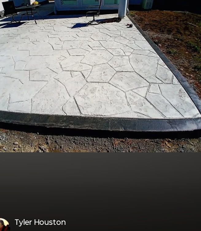White stamped-concrete patio with a curved edge beside dirt and a blue chair in the background