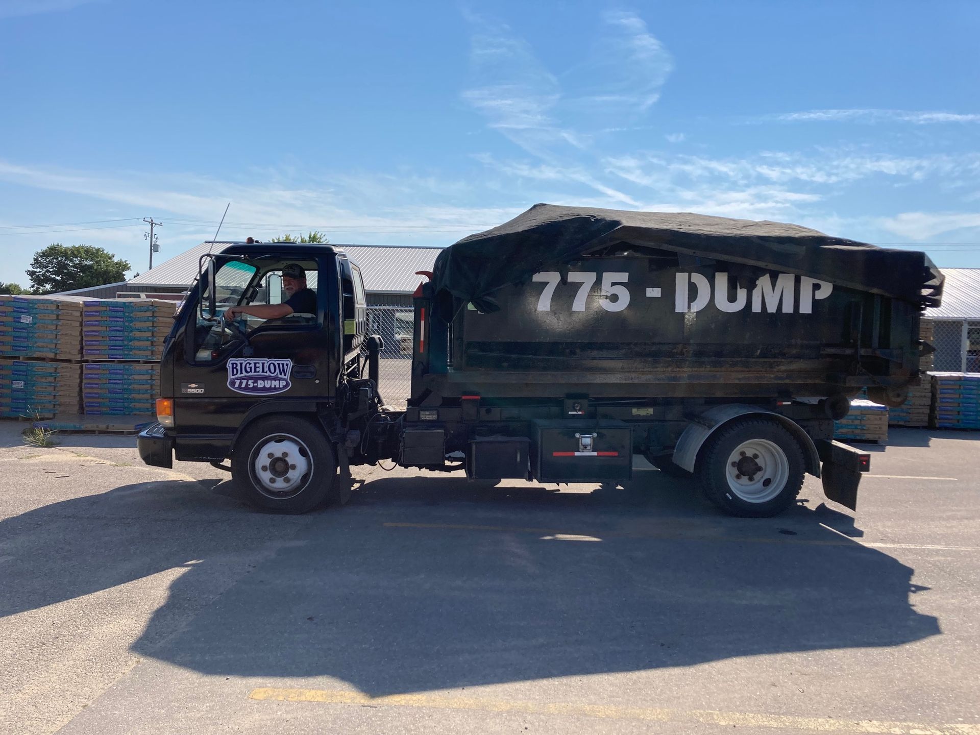 A blue dumpster is parked in front of a house under construction.