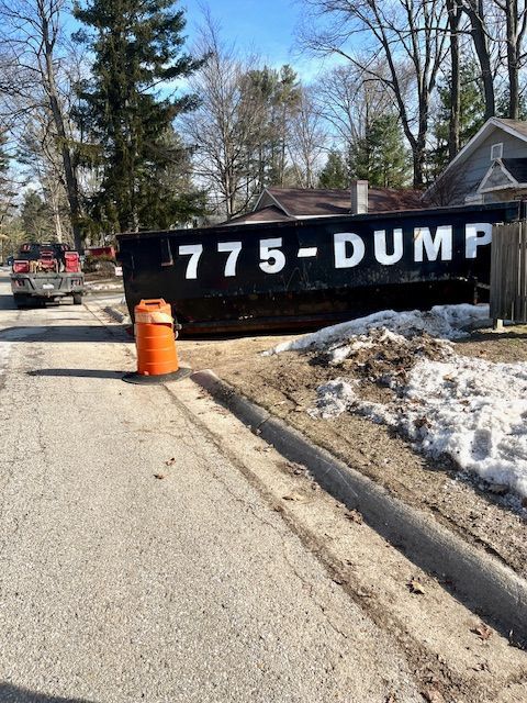 A black dumpster is parked on the side of the road
