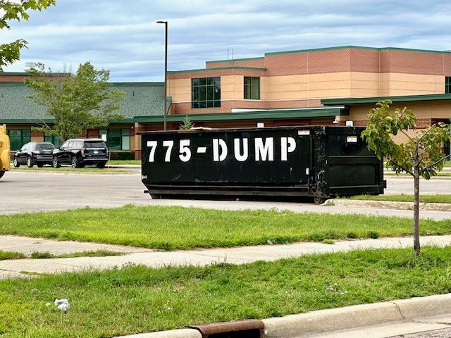 A black dumpster with the number 775-dump painted on it