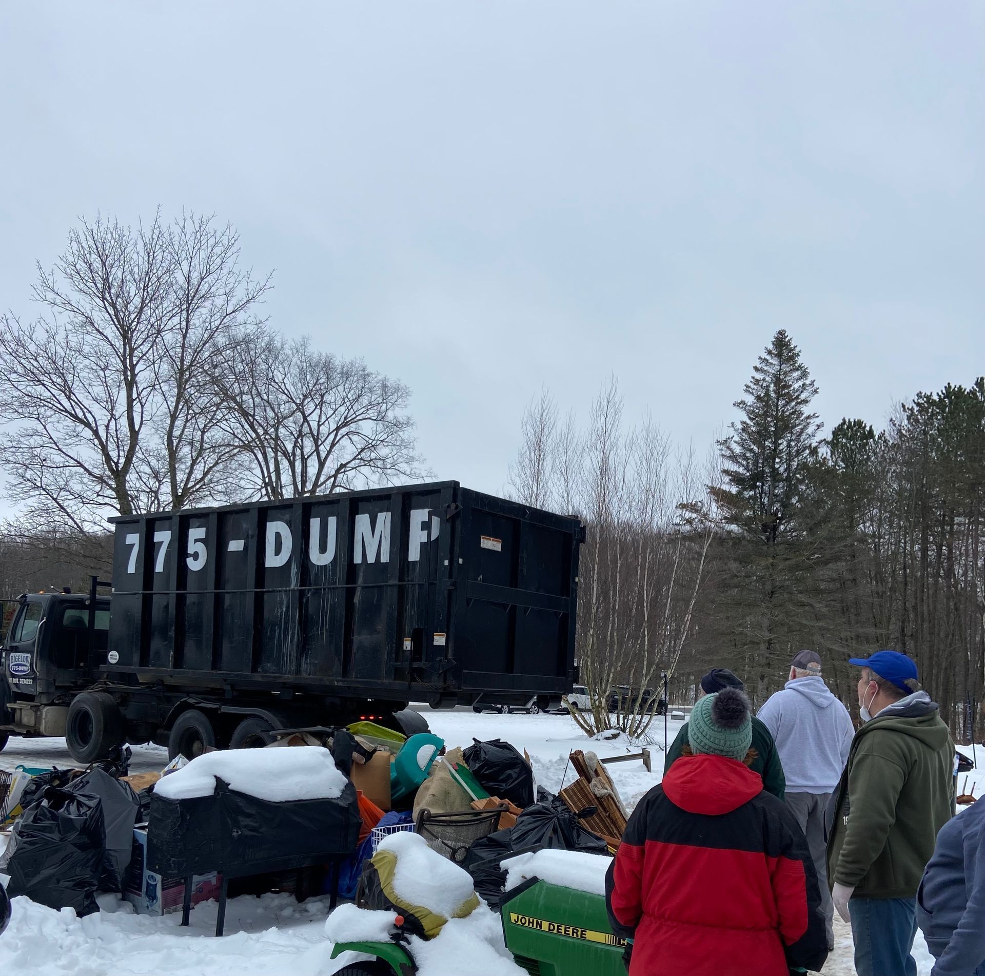 A group of people standing around a dumpster that says 175 dump