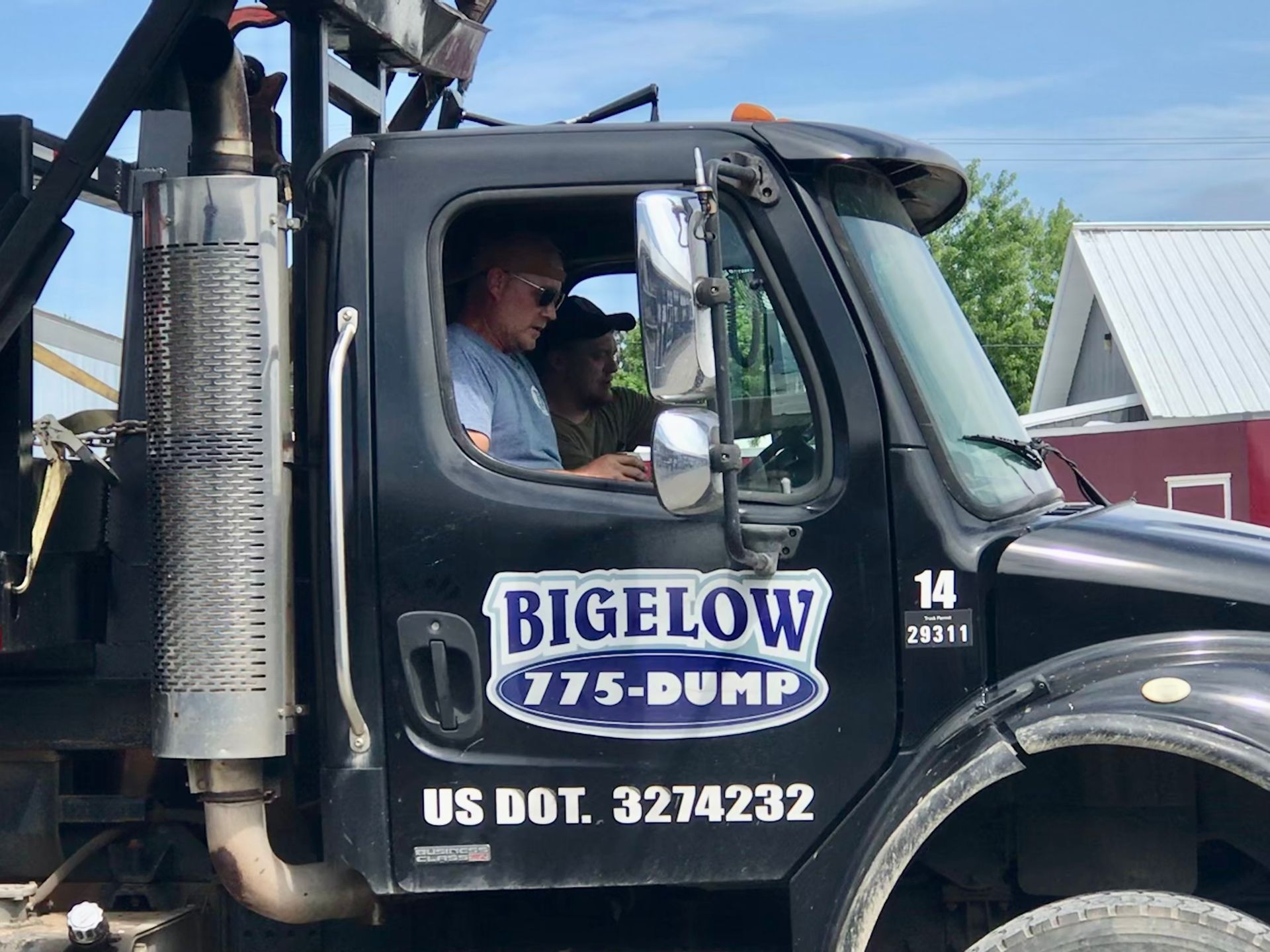 A man is sitting in the driver's seat of a Bigelow dump truck