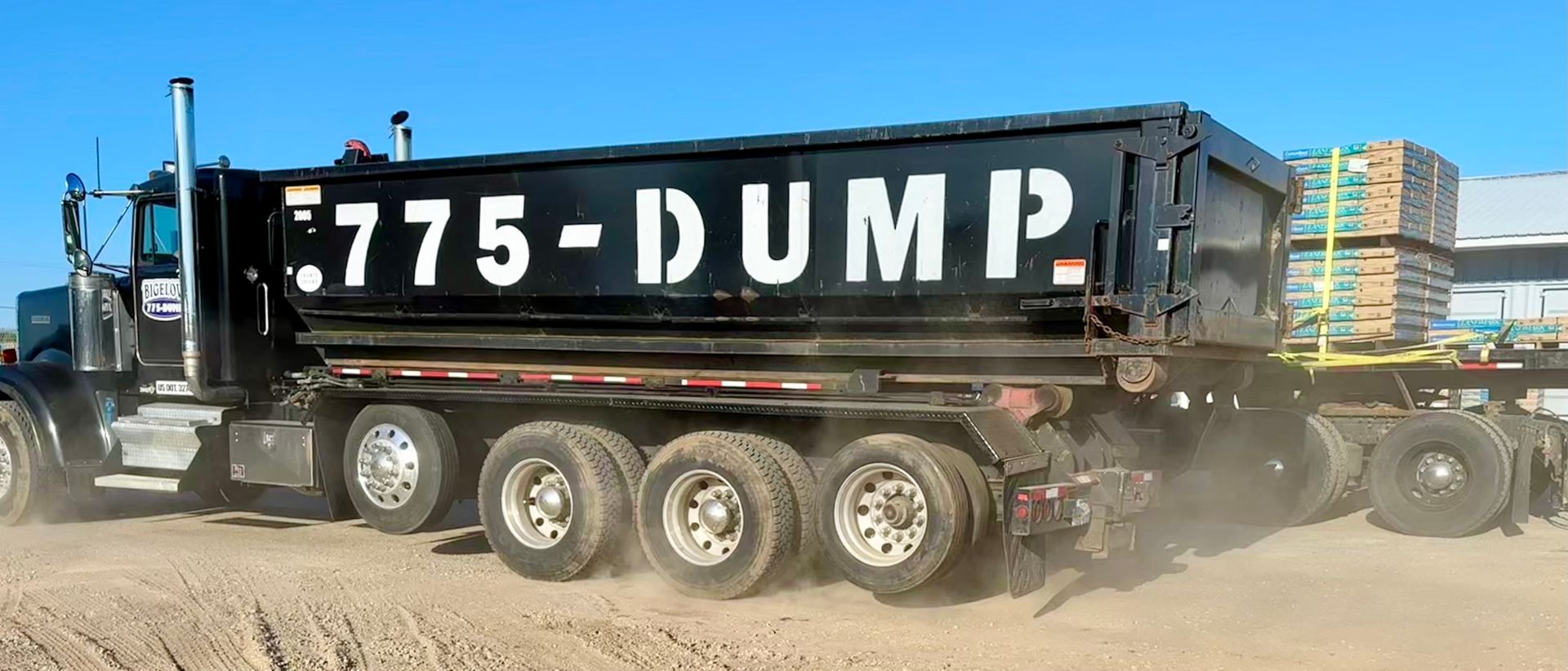A dump truck is driving through a dirt field