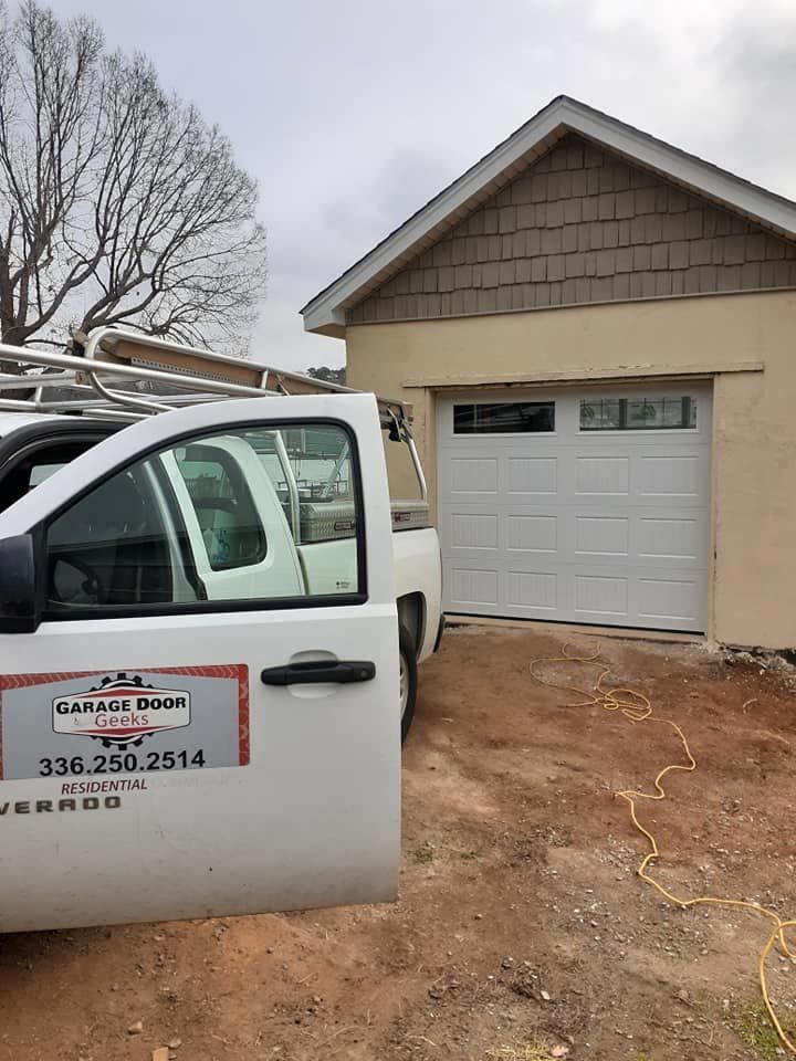 A white truck is parked in front of a garage door.