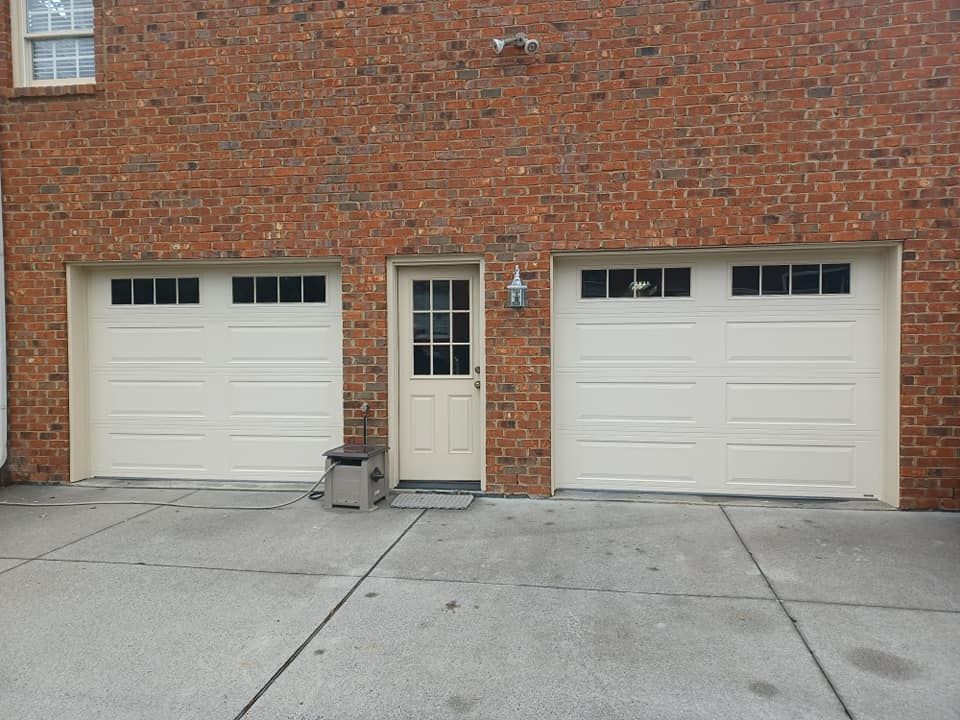A brick building with two white garage doors and a door