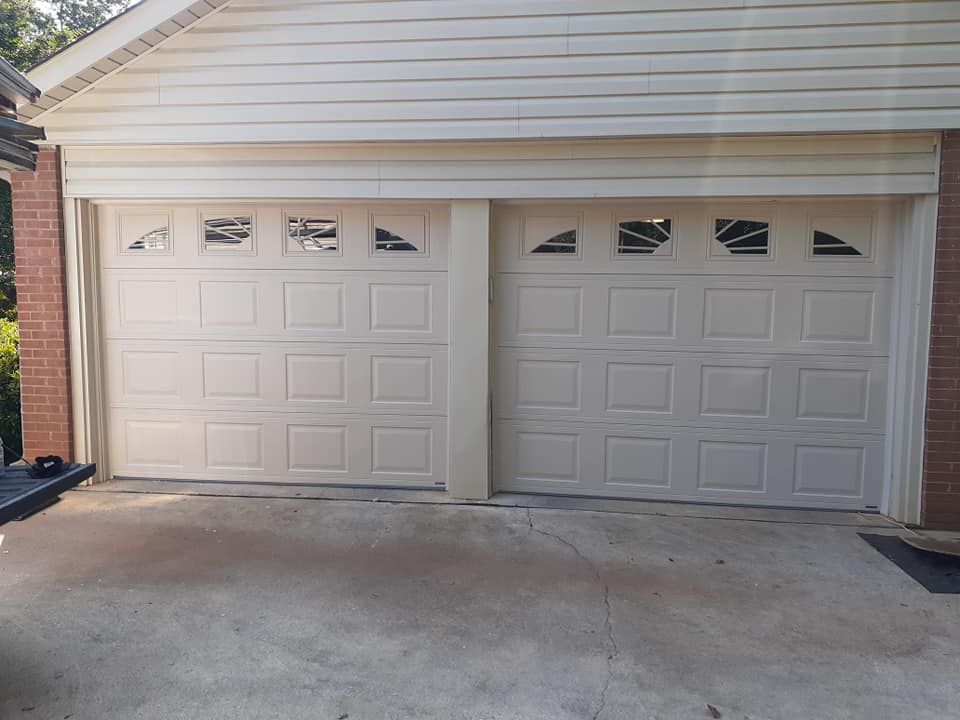 A white garage door is sitting in front of a brick house.