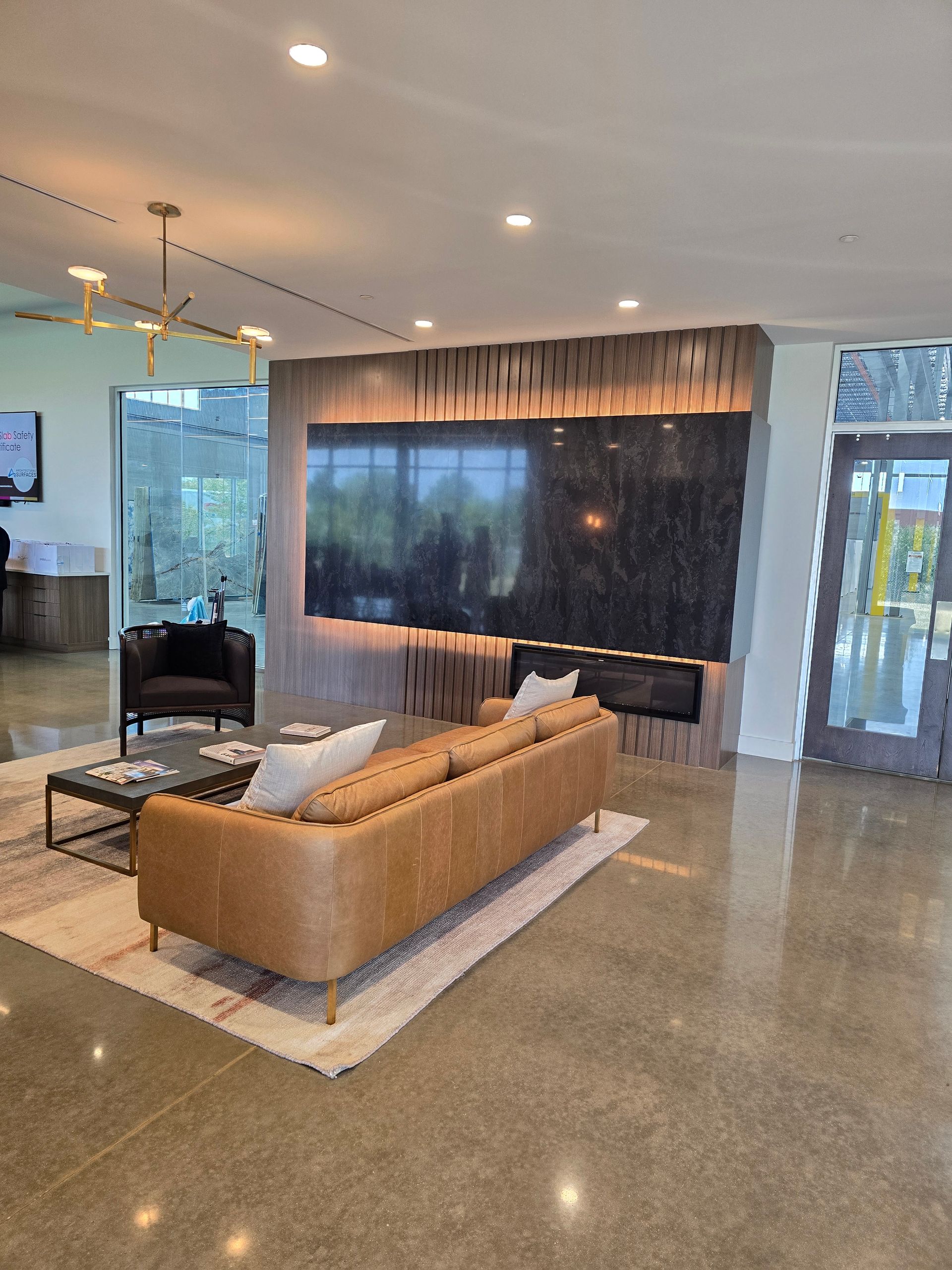 Modern living room with leather sofa, fireplace, and large screen television. Polished concrete floor.