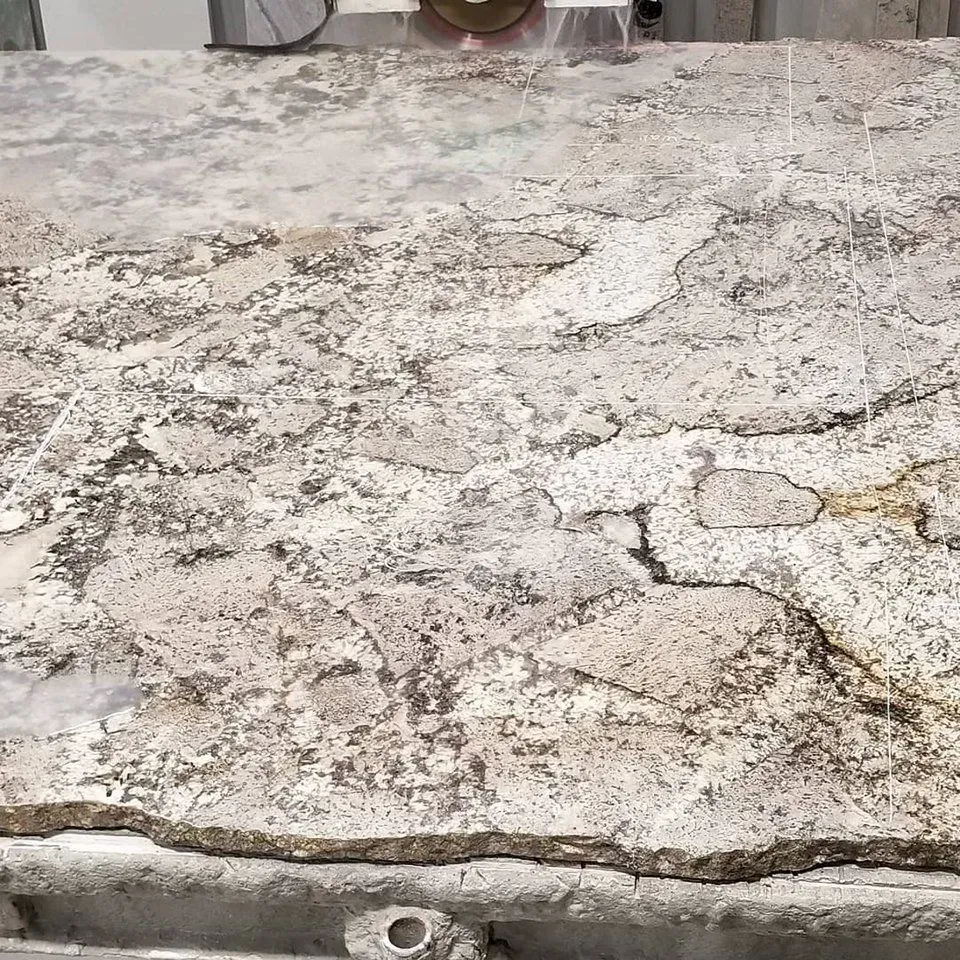 Granite countertop being cut with a saw, showing a mix of beige, white, and gray colors.