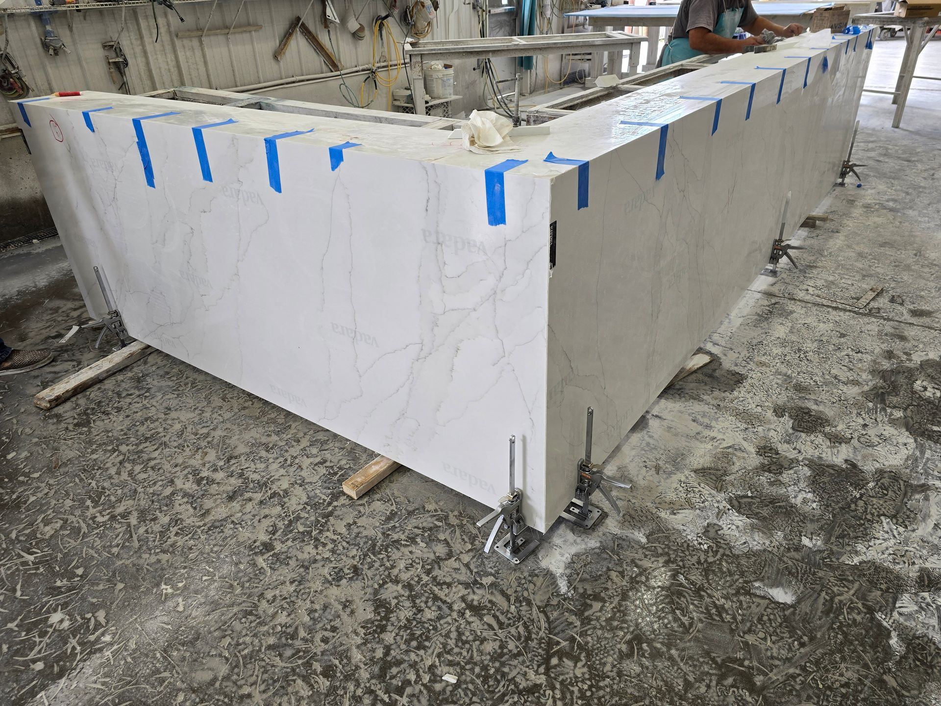 Large white countertop sections joined with blue tape, industrial setting.