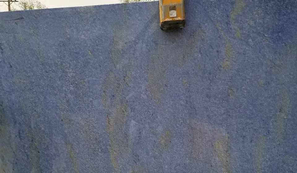 Blue granite slab with golden veining and tool.