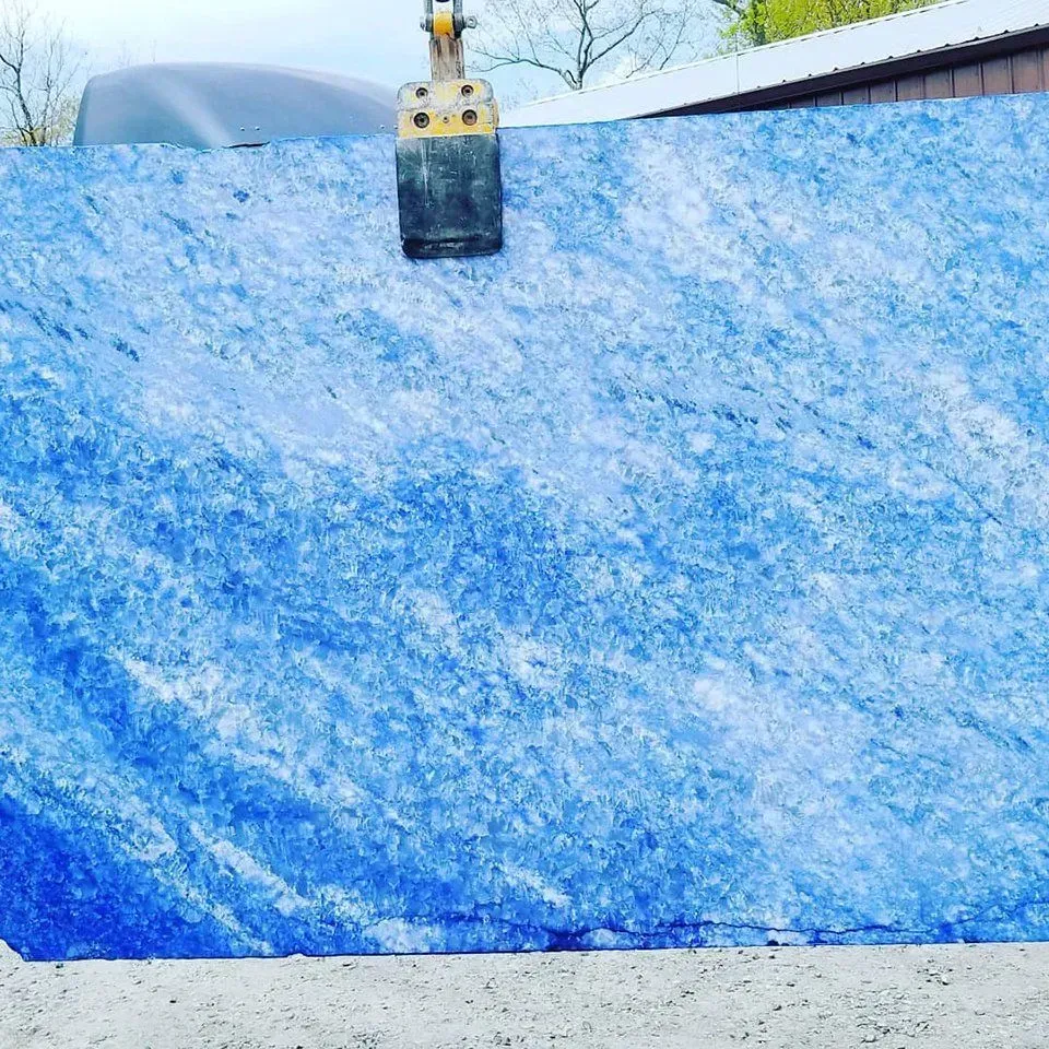 Blue slab of stone being lifted by a construction vehicle.