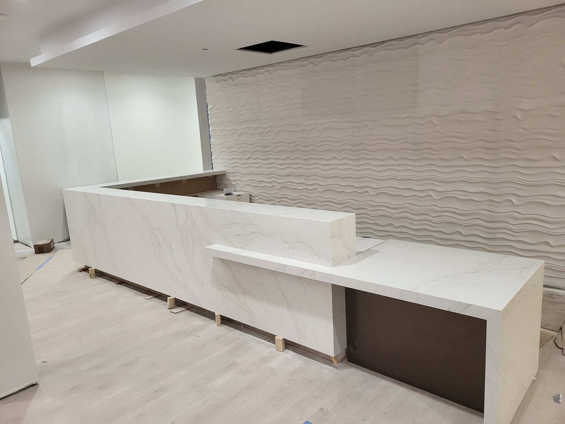 White and gray reception desk in a room under construction.