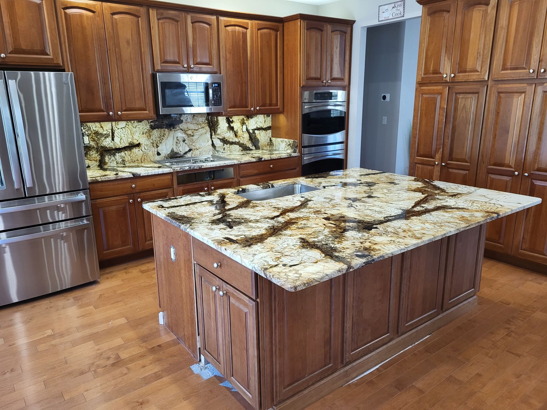 Kitchen with wooden cabinets, granite countertops, and stainless steel appliances, including an island.