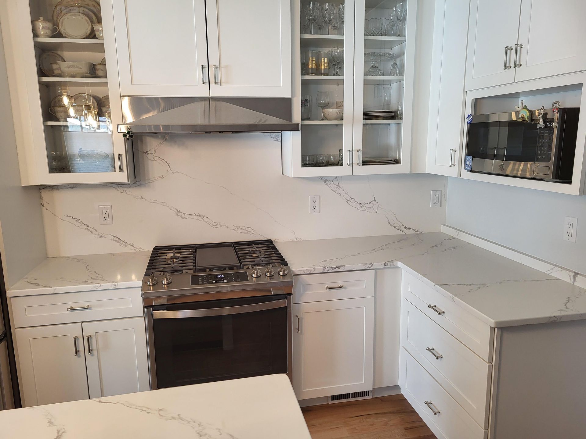 White kitchen with stainless steel appliances, white cabinets, and a quartz countertop.