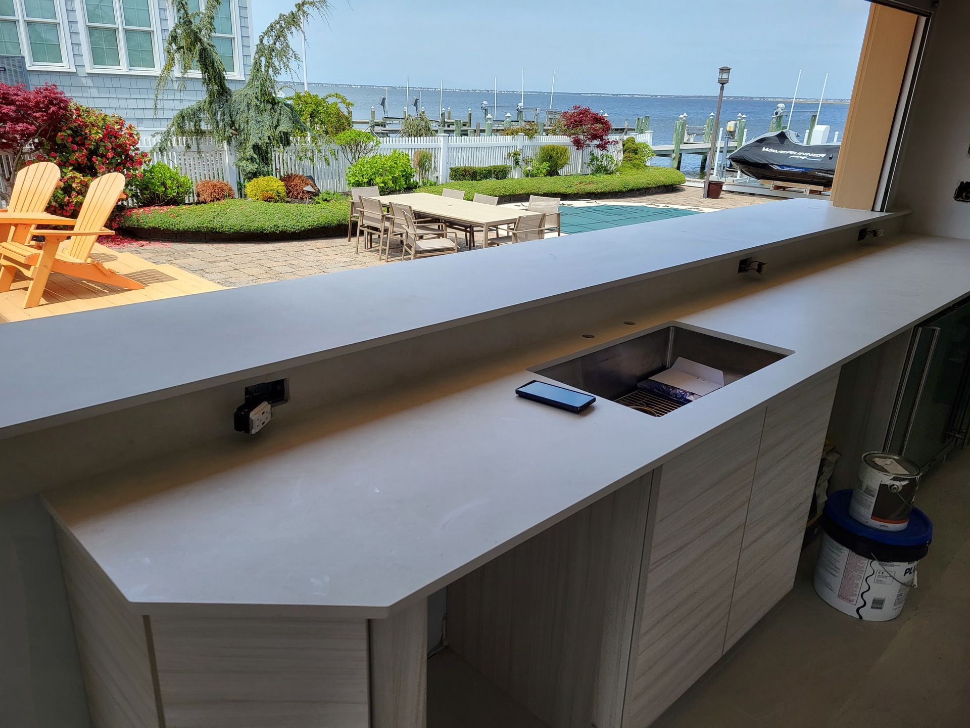 Outdoor kitchen with a countertop, sink, and view of pool and water.