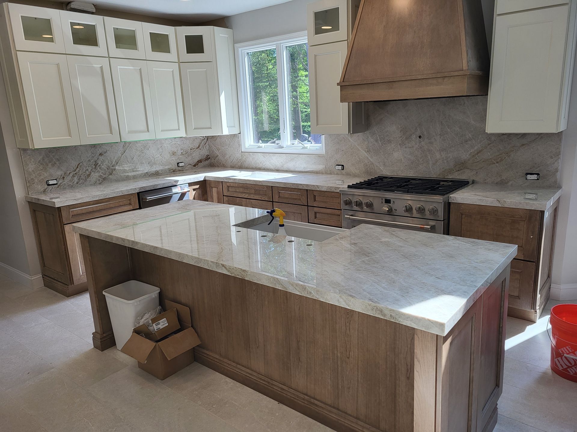 A kitchen with white and wood cabinets, granite countertops, and a central island.