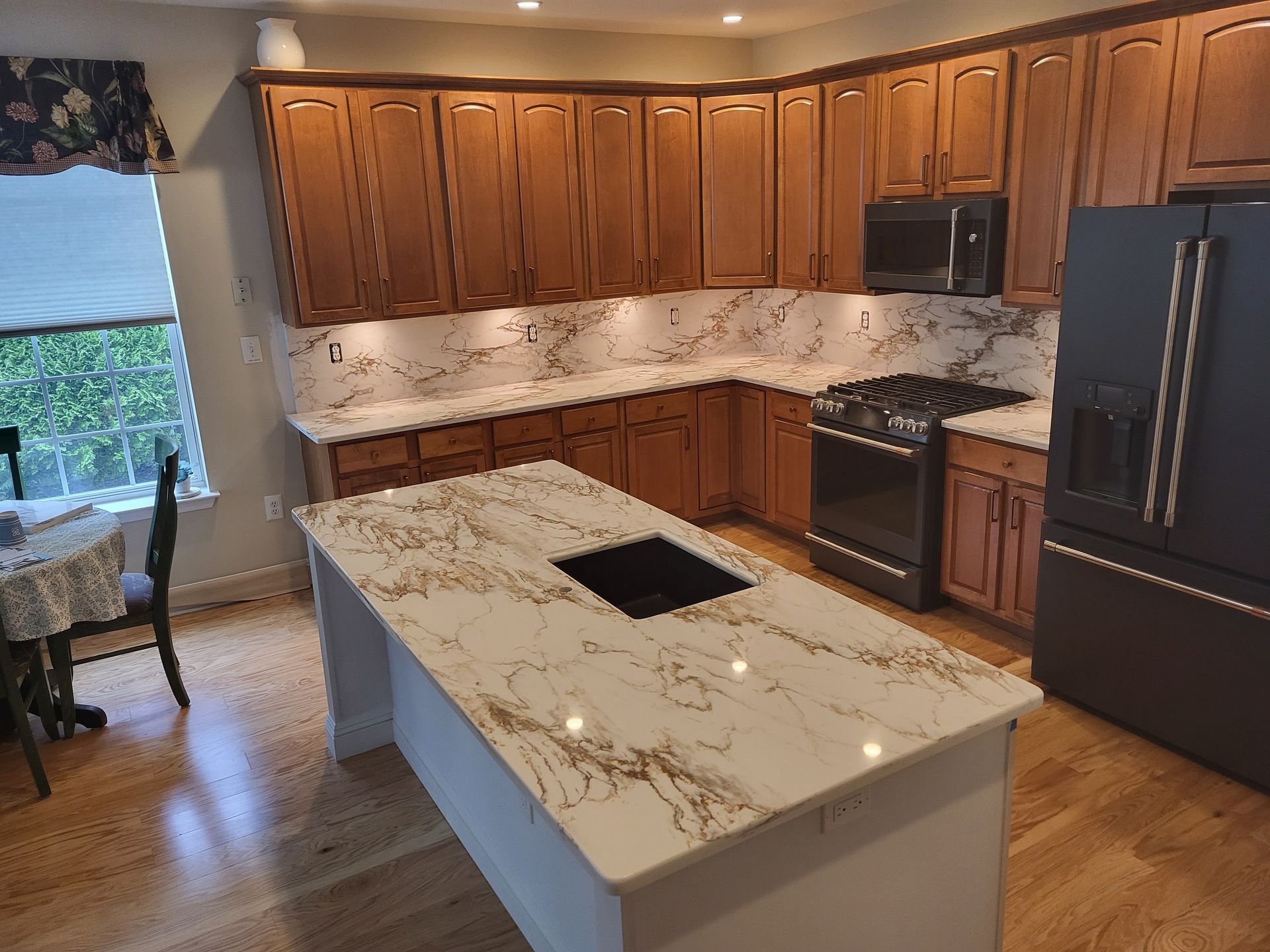 Kitchen with wood cabinets, white countertops, and black appliances.
