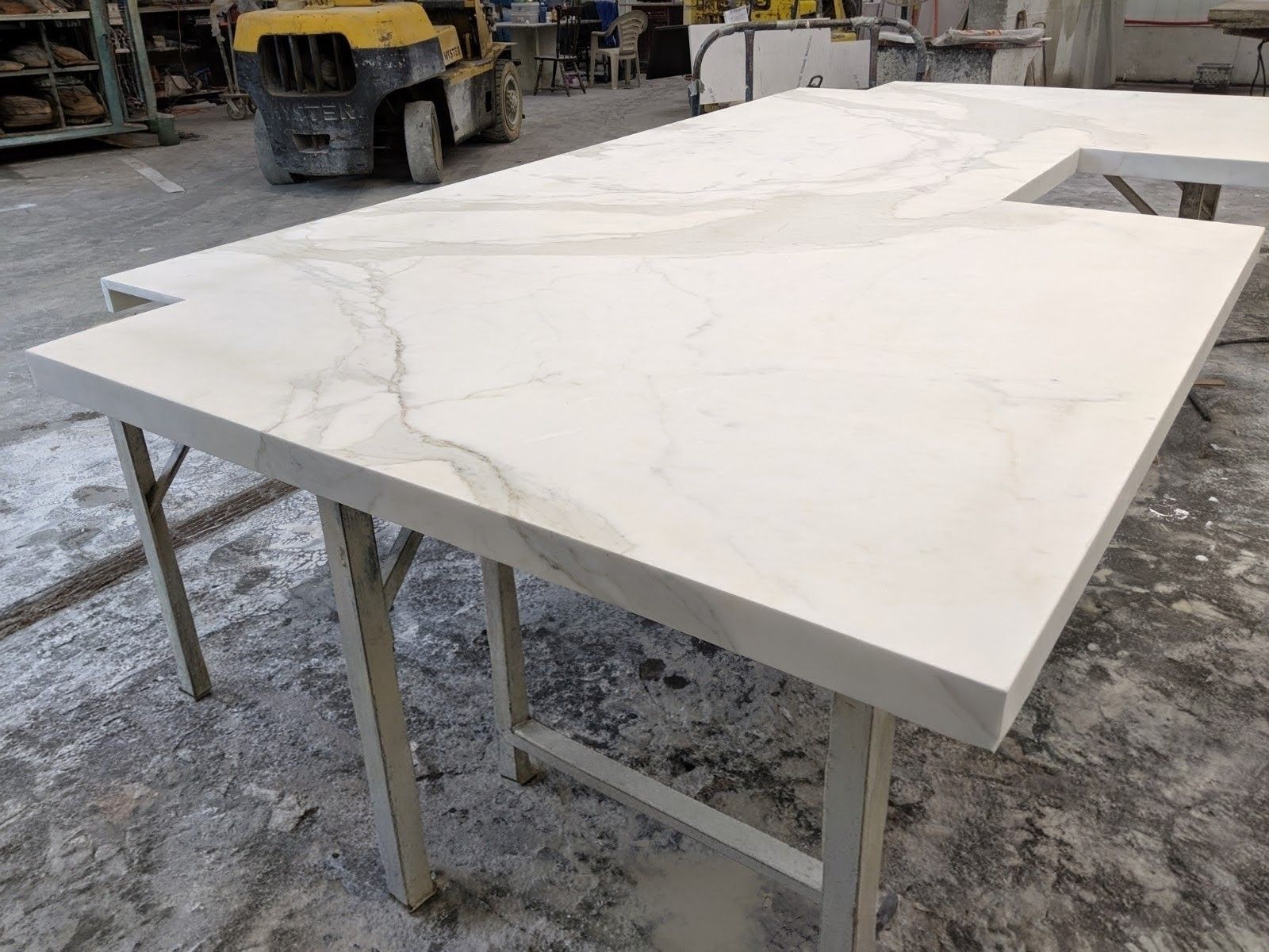 White marble countertop with veining, on a metal sawhorse in a workshop.