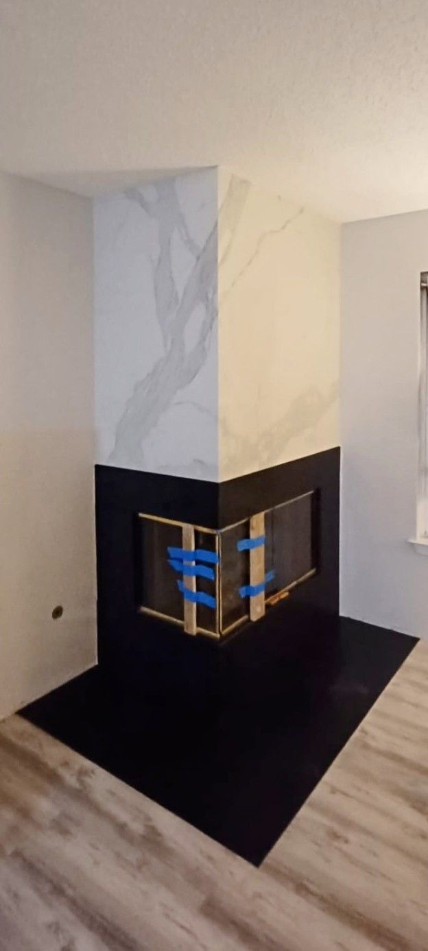 Corner fireplace with black hearth, black lower section, and marble-like upper section.