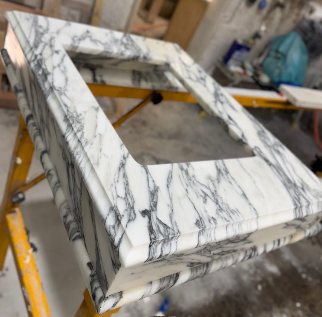 White marble countertop with gray veining, rectangular opening, on yellow scaffolding.