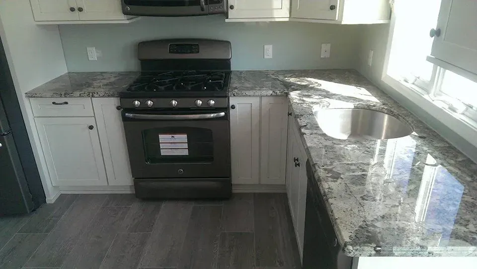 Kitchen with white cabinets, gray countertops, and a black stove.
