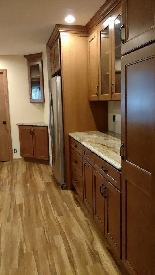 Kitchen with wood cabinets, stainless steel refrigerator, and wood-look flooring.